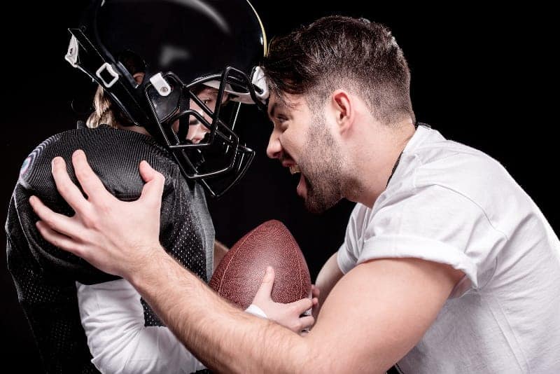 Angry coach holding football player | Obnoxious Youth Sports Parents: Your Role As Coach