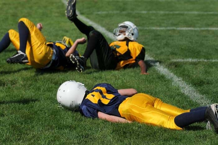 Football players on the ground | What are the Responsibilities of a Youth Sports Coach?