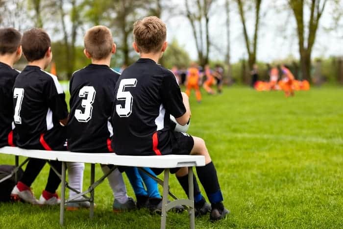 Kids sitting on the bench | What are the Responsibilities of a Youth Sports Coach?