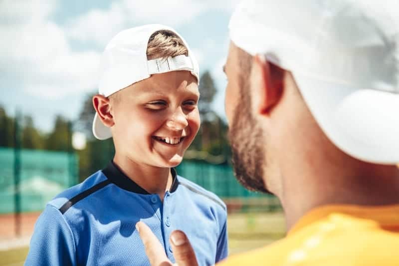 Young boy smiling looking at coach | What are the Challenges of Coaching Youth Sports?