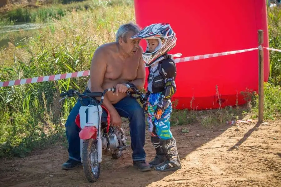 Man with no shirt on talking to young motorbike rider | What Makes a Bad Youth Sports Coach? How to Not Become One