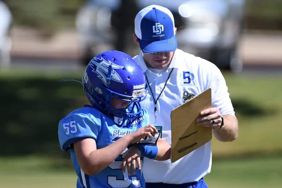 Young football coach talking to coach with clipboard | Why Do Sports Coaches Need To Be Organized?