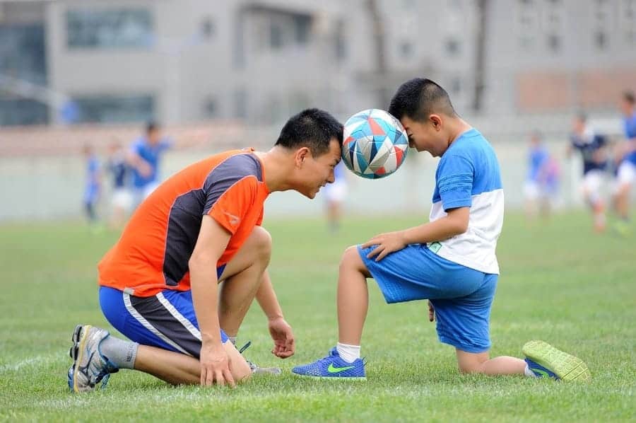 Soccer coach and young player heading the ball | Why It's Essential For Coaches to Have Favorites