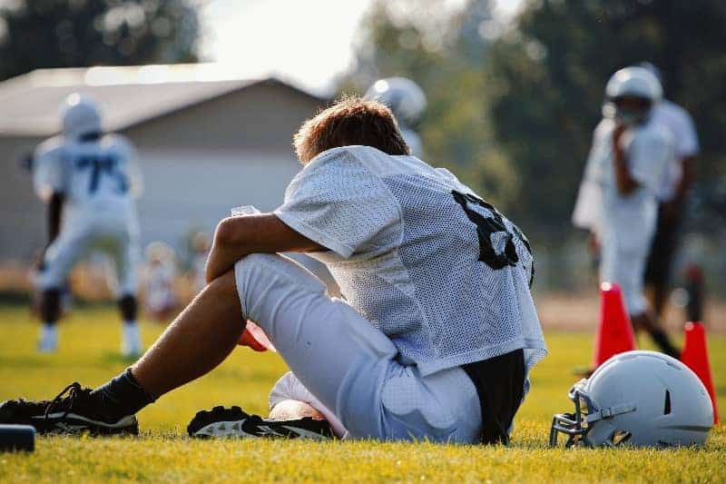 Football player sitting on the ground | Why It's Essential For Coaches to Have Favorites