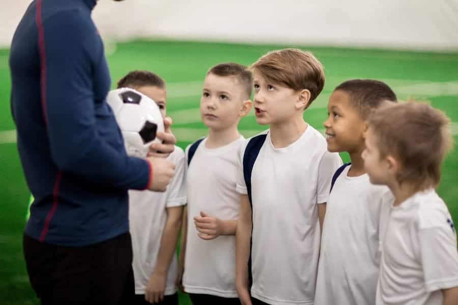 Young boys talking to soccer coach | How Beginner Youth Sports Coaches Can Earn Player Respect