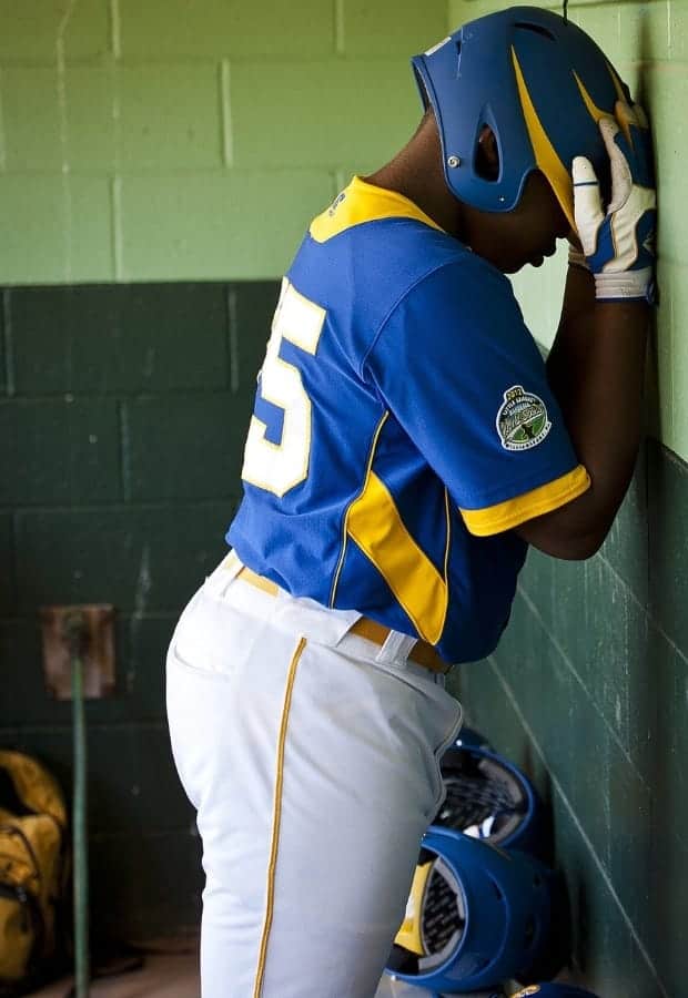 Baseball player standing against wall | Why Do Youth Coaches Bench Good Players?
