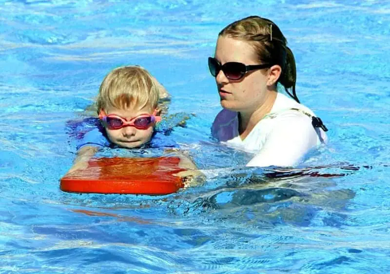 Swimming coach with boy in water wearing goggles | How To Coach 8 and Under Swimmers