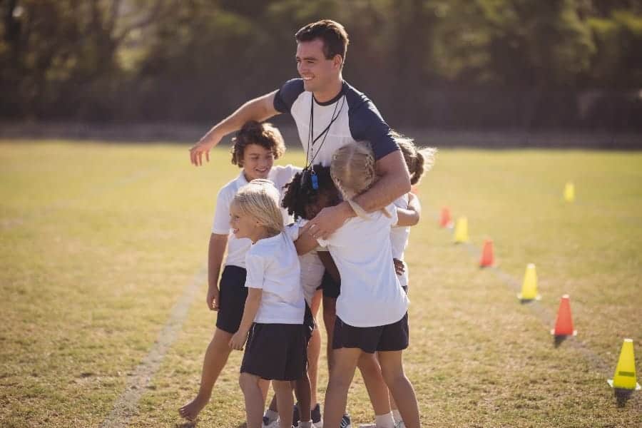Players and male coach smiling | How Beginner Youth Sports Coaches Can Earn Player Respect